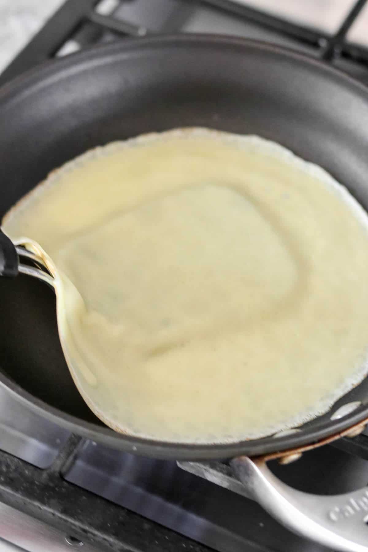 Three Swedish pancakes folded with a dusting of powdered sugar and berries on a plate.