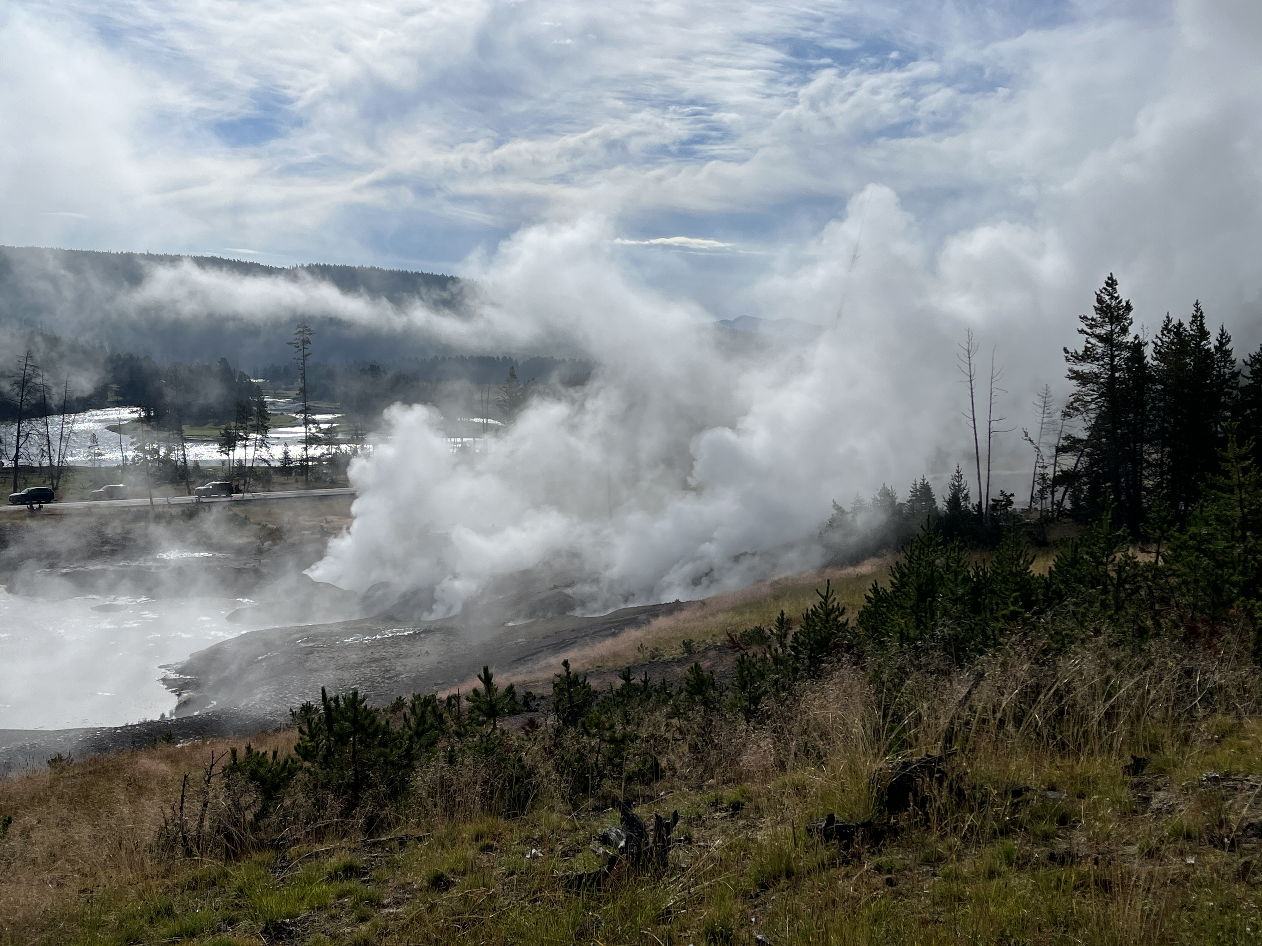 A large spring with clouds of sulfur smoke rising from it.